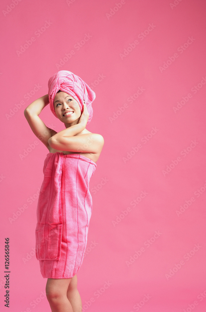 Woman wrapped in a pink towel, wearing pink turban, looking away