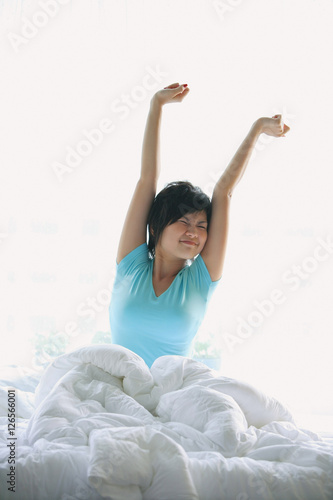 Woman stretching in bed, arms raised