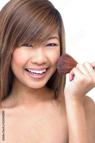 Teenage girl holding make-up brush to face