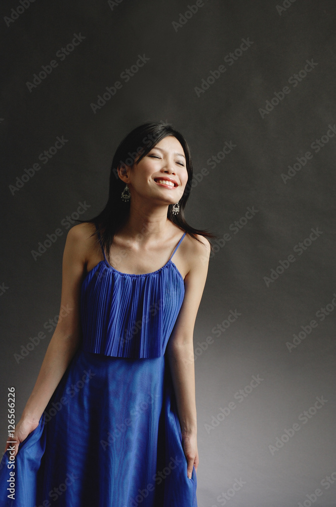 Obraz premium Woman in blue dress, eyes closed, smiling