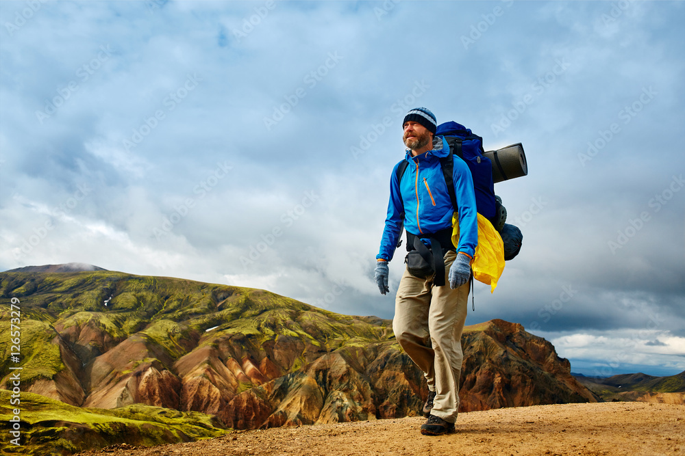Naklejka premium man hiker on the trail in the Islandic mountains. Trek in National Park Landmannalaugar, Iceland