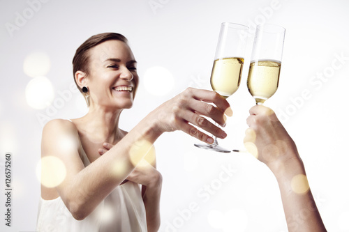 Woman celebrating and says cheers at the party with a glass of champagne. Clang glasses together