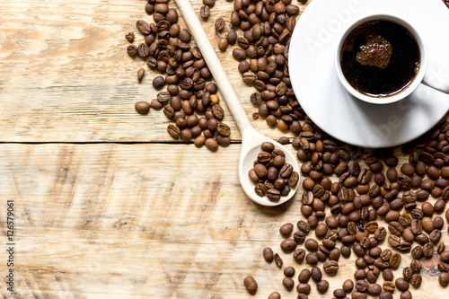 cup of coffee, beans and spoon on wooden background