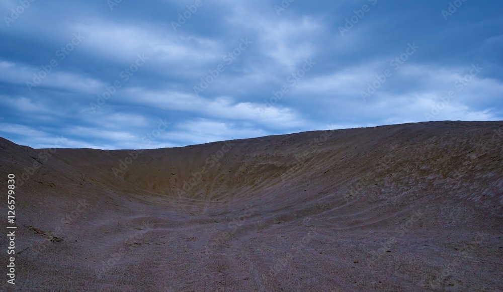 Sand dunes under cloudy sky at evening
