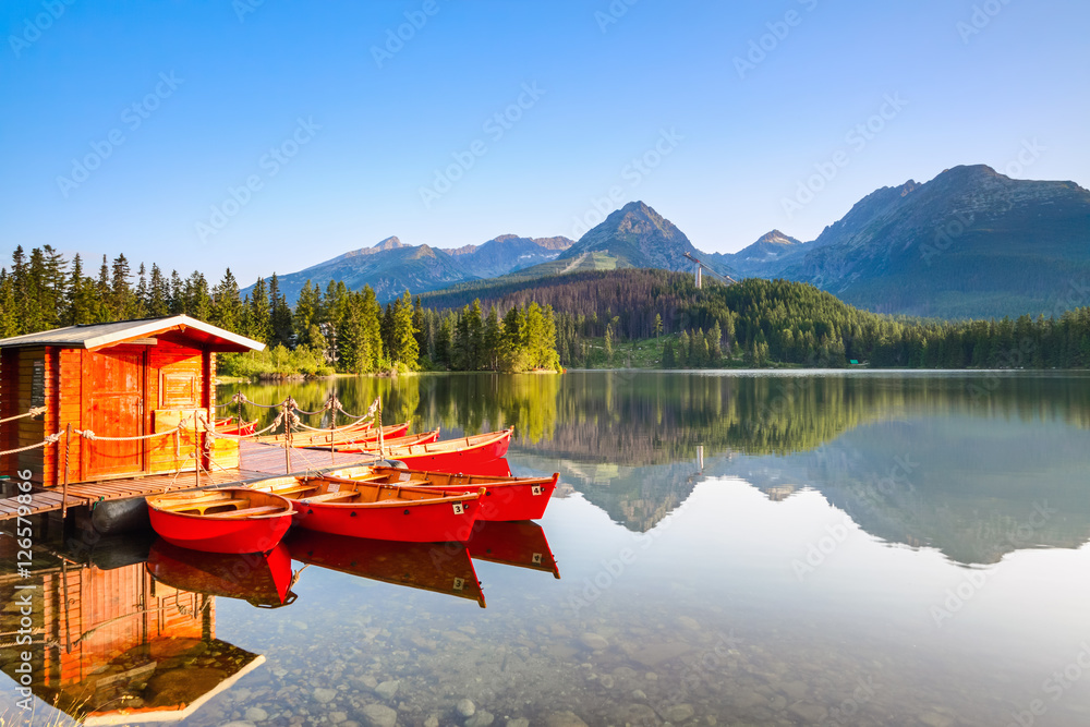 Red boats moored at wooden house on a lake.