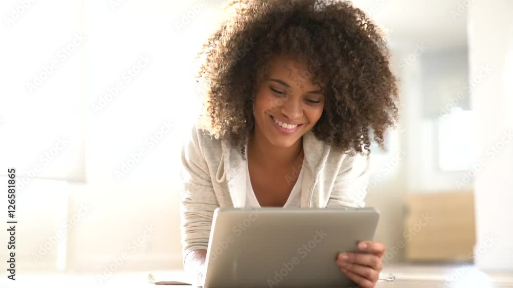 Relaxed mixed-race girl laying on floor connected with tablet Relaxed mixed-race girl laying on floor connected with tablet