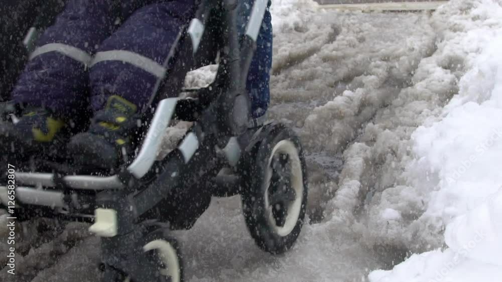A dad pushing a stroller in slushy snow on a wintery day. Slow motion clip. A dad pushing a stroller in slushy snow on a wintery day. Slow motion clip.