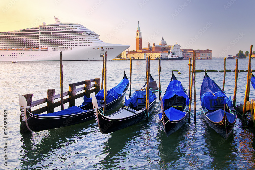 Venice with gondolas on Grand Canal against San Giorgio Maggiore church in Italy with large cruise ship in beautiful summer morning sunrise light