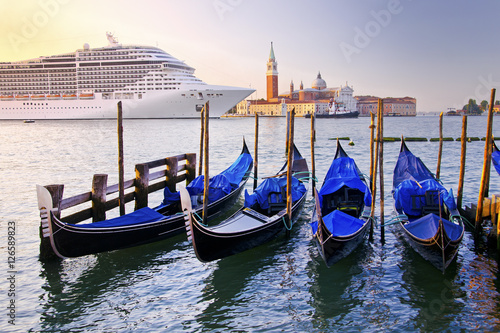 Venice with gondolas on Grand Canal against San Giorgio Maggiore church in Italy with large cruise ship in beautiful summer morning sunrise light