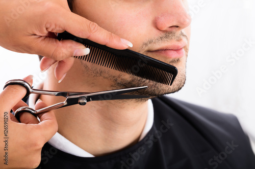 Hairdresser Shaping Man's Beard With Scissor And Comb