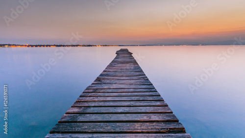 Fototapeta Naklejka Na Ścianę i Meble -  Long Wooden Wharf on Garda lake at sunset
