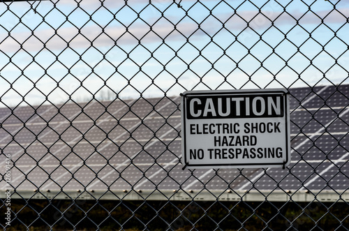 Solar panel array behind a chain link fence with Electric Shock