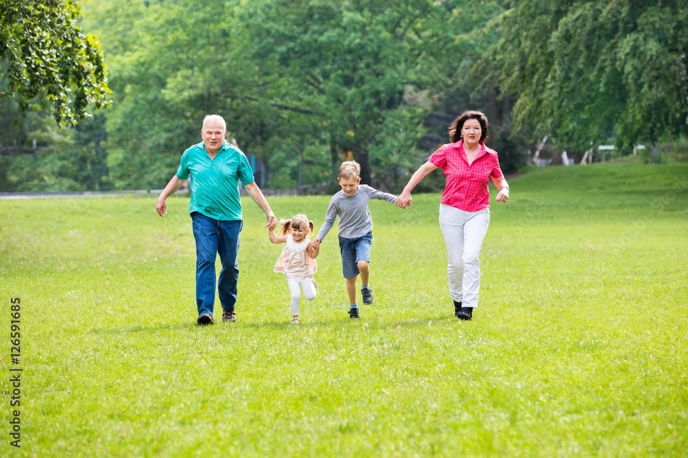 Grandparents And Grandchildren Running In Park
