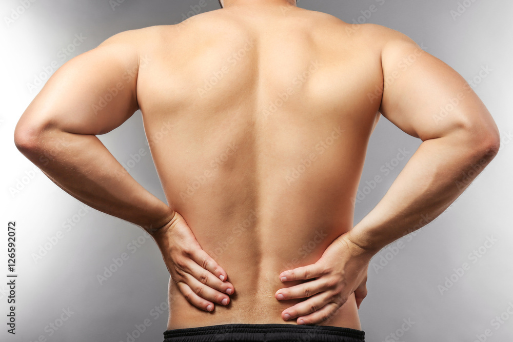 Man with backache on grey background
