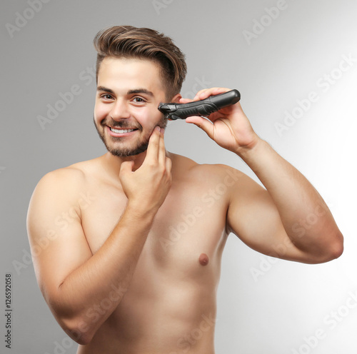 Handsome man shaving on gre...