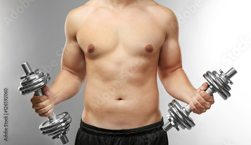 Sporty man with dumbbells o...
