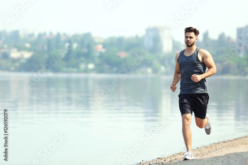 Handsome man jogging on river bank