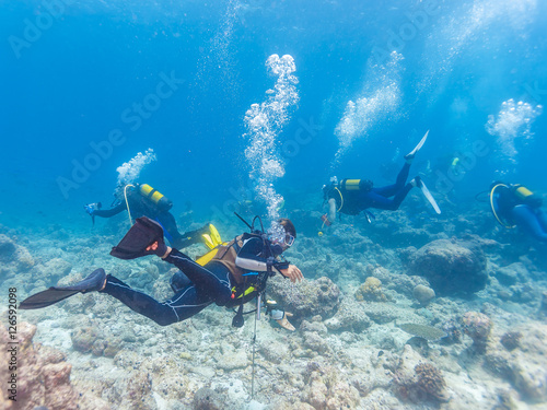 Group of underwater scuba divers with guide, Maldives