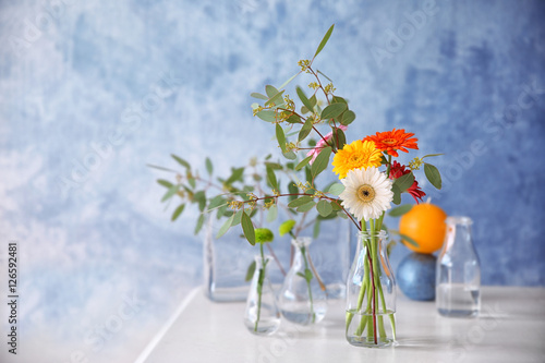 Flowers in vase on color background