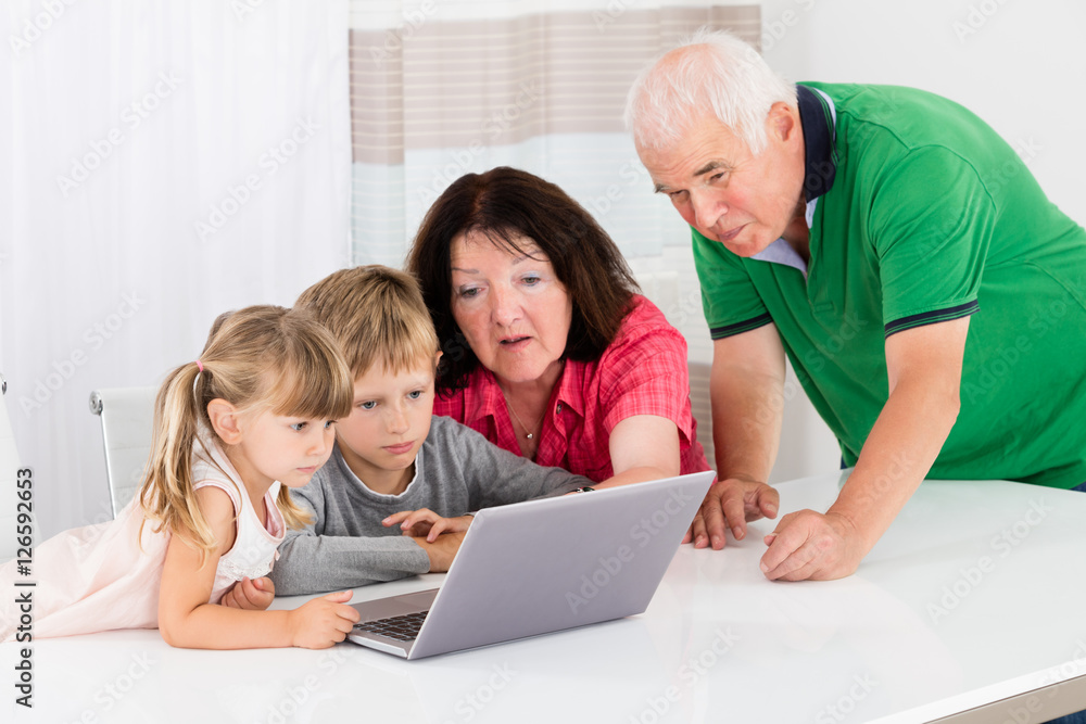 Happy Grandmother With Her Grandchildren Using Laptop Happy Grandmother With Her Grandchildren Using Laptop