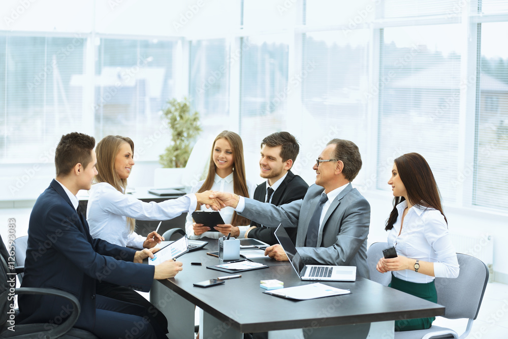 Business meeting at the table and handshake of business partners Business meeting at the table and handshake of business partners