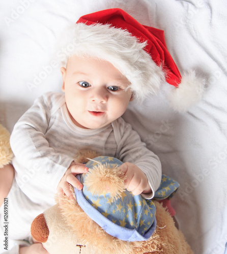 cute baby in costume of Santa Claus with a toy.
