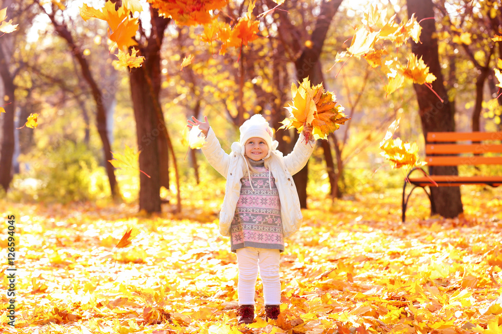 Cute little girl playing with leaves in autumn park on sunny day Cute little girl playing with leaves in autumn park on sunny day