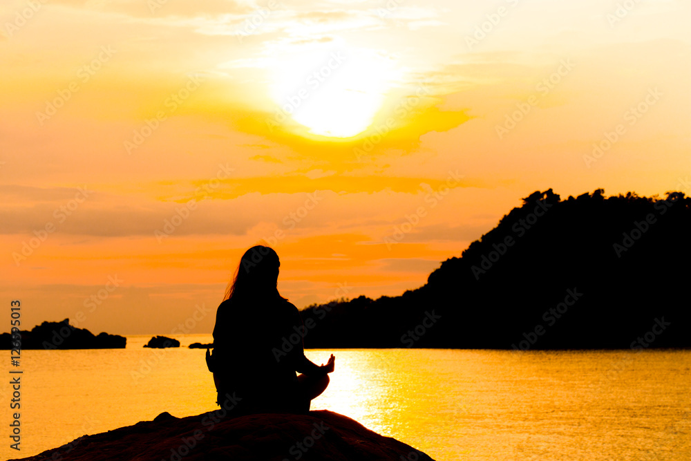 Silhouette, Woman Meditating in Yoga pose or Lotus Position by t