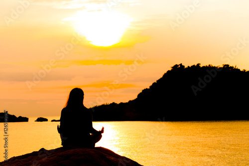 Silhouette  Woman Meditating in Yoga pose or Lotus Position by t