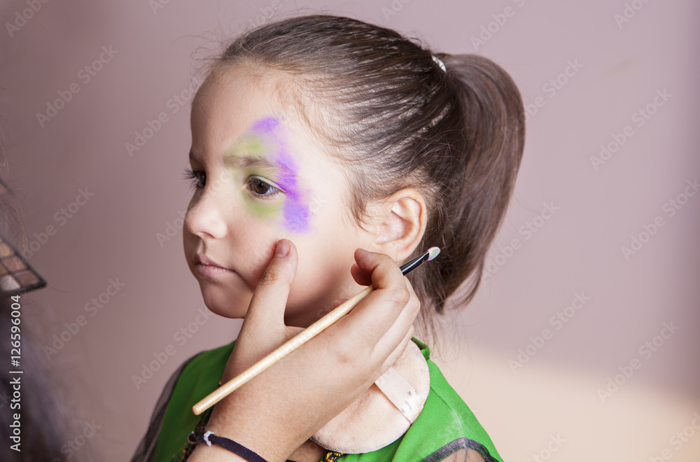 Little cute girl making facepaint before halloween party Little cute girl making facepaint before halloween party