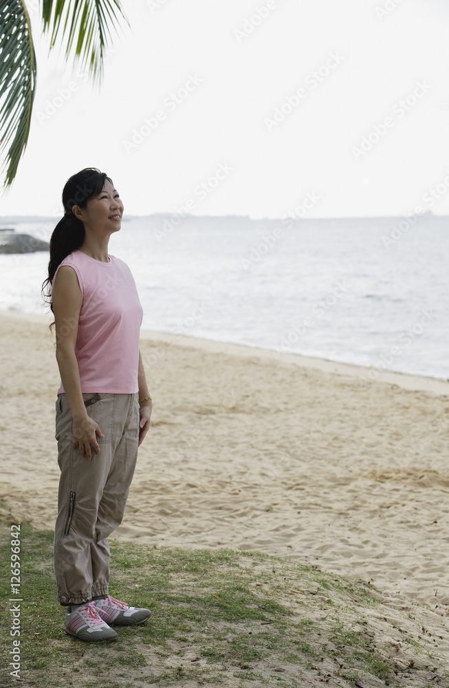 Woman standing on beach, smiling