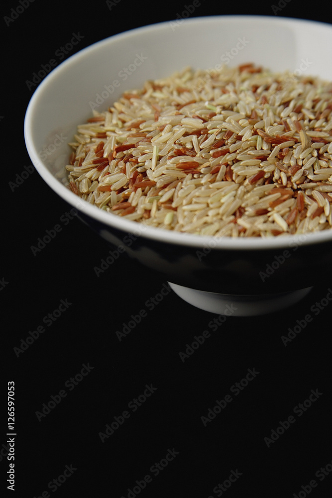 Bowl of uncooked rice against black background Bowl of uncooked rice against black background