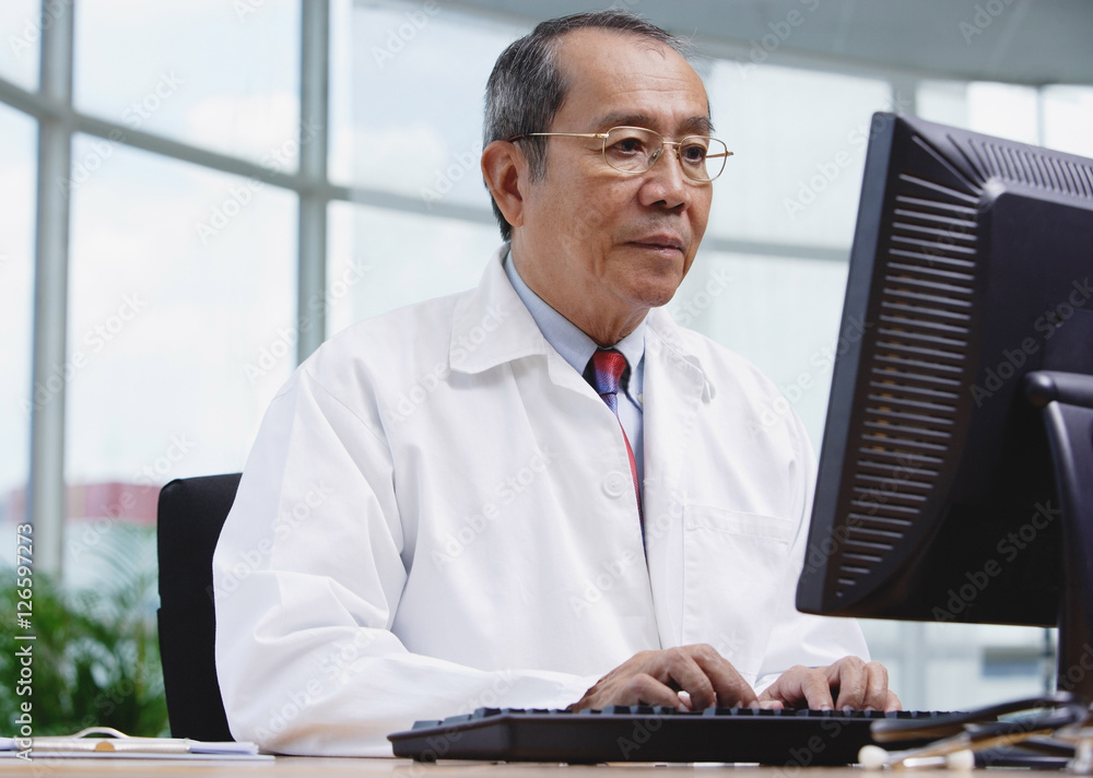 Doctor in office, using desktop computer