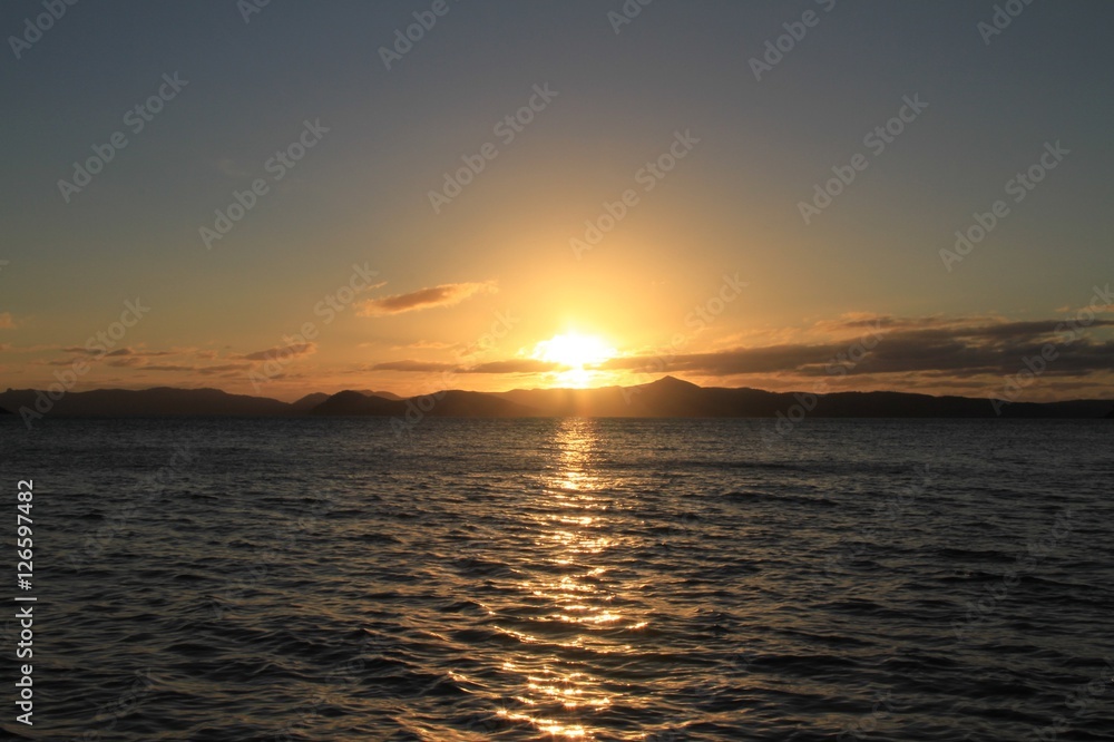 Obraz premium Sunrise over the Whitsunday Islands QLD Australia with reflections of the sun on the water