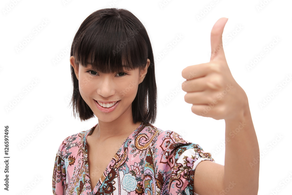 Young woman smiling at camera, making thumbs-up sign Young woman smiling at camera, making thumbs-up sign