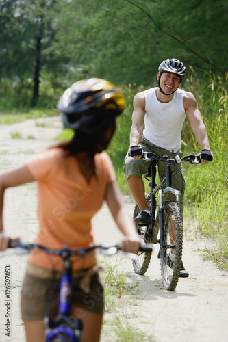 Couple cycling, woman in foreground turning to look at man in the background