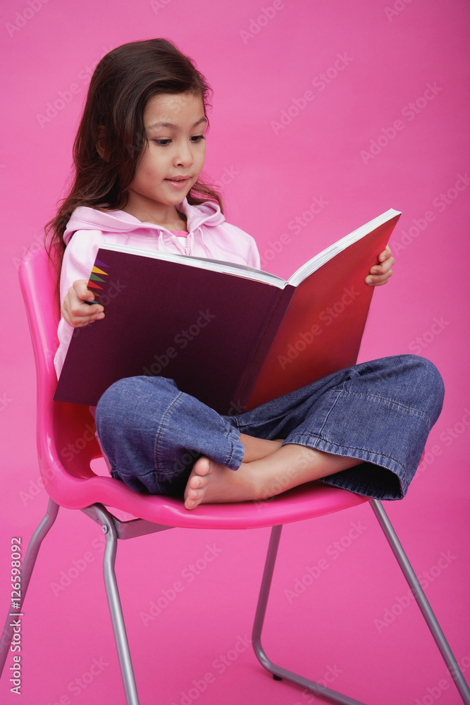 Girl sitting on chair, reading book
