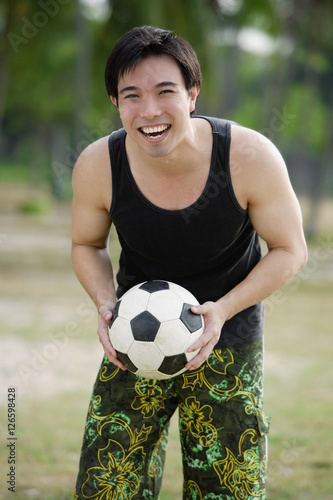 Man holding soccer ball, smiling at camera © Alexander