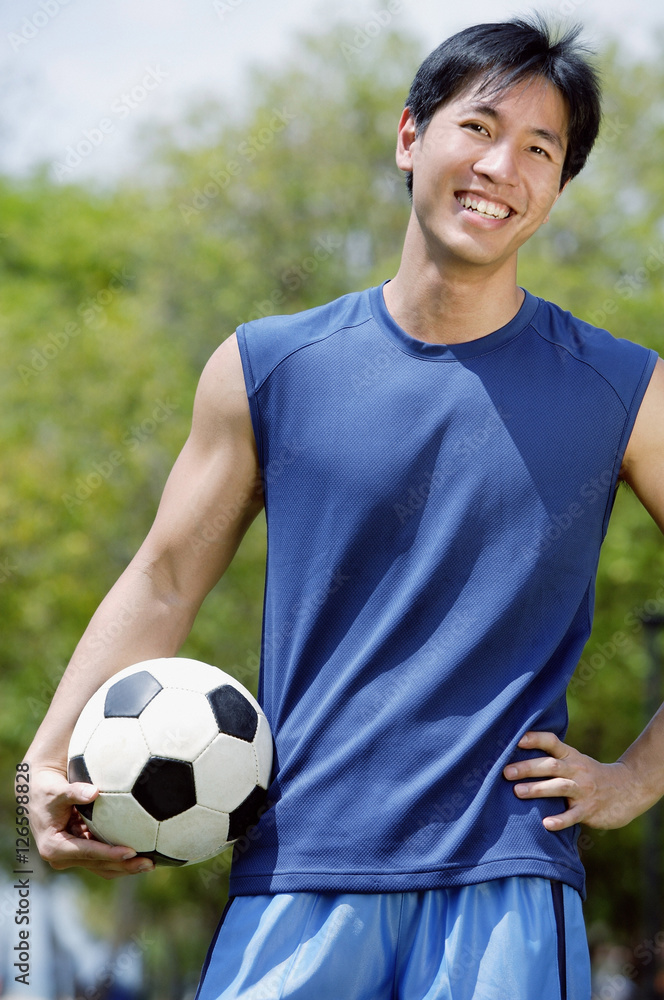 Man holding soccer ball, looking at camera Man holding soccer ball, looking at camera