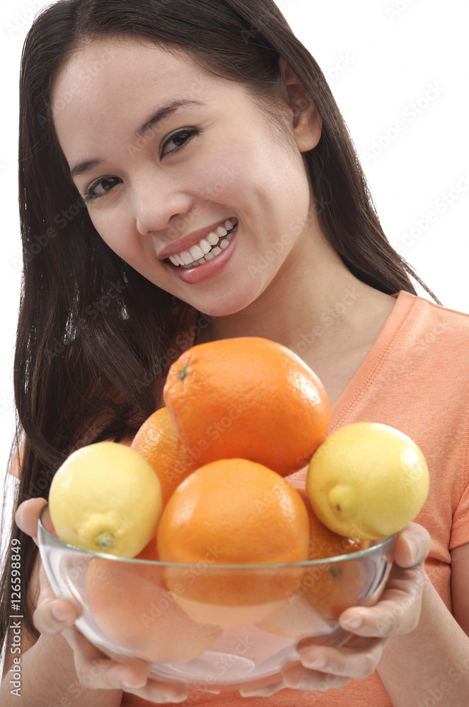 Young woman holding bowl of oranges and lemons Young woman holding bowl of oranges and lemons