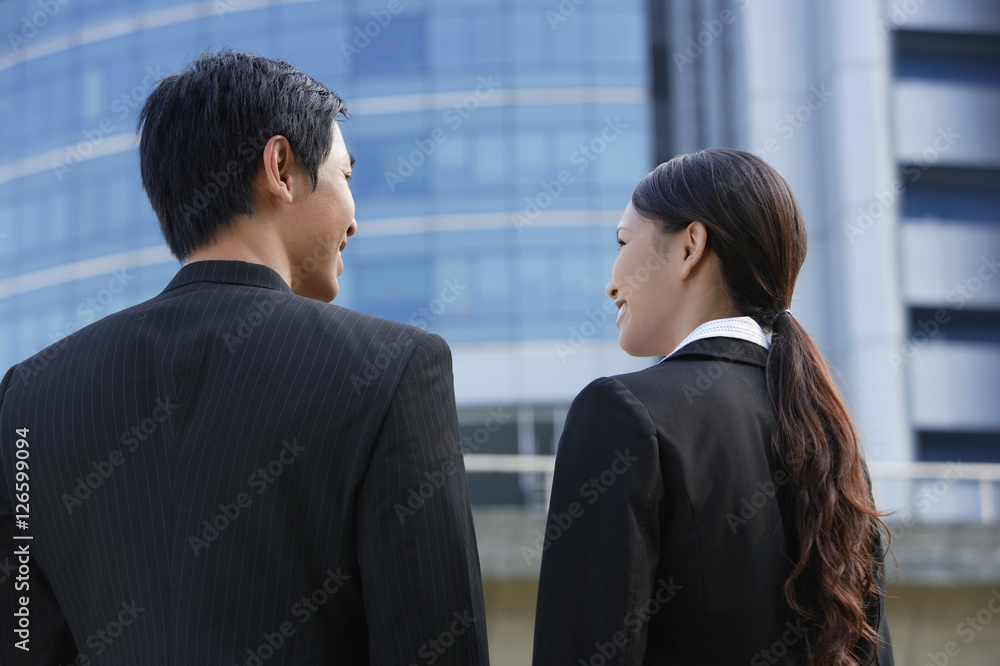 Executives standing side by side, talking, rear view Executives standing side by side, talking, rear view