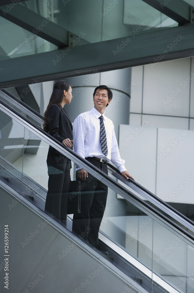 Businessman and businesswoman on escalator Businessman and businesswoman on escalator