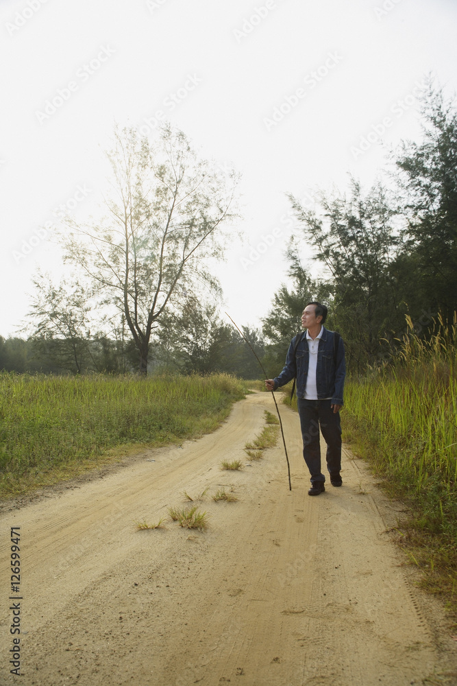 Man walking down dirt road, hiking