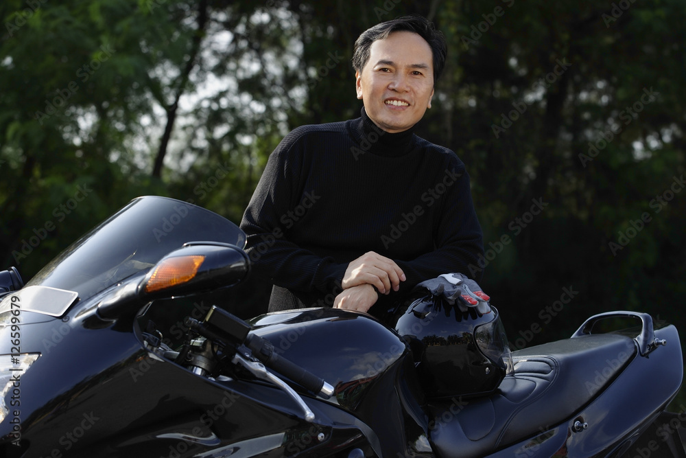 Man standing by black motorcycle, smiling at camera