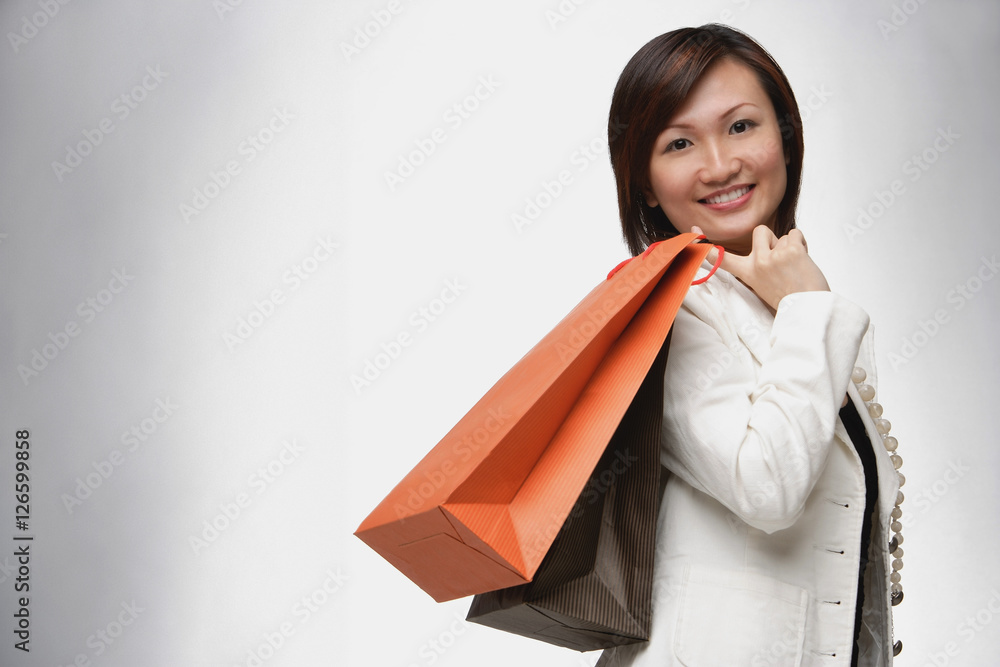 Businesswoman carrying shopping bags over shoulder, smiling Businesswoman carrying shopping bags over shoulder, smiling