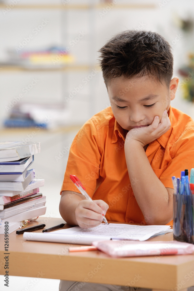 Boy sitting at desk, doing homework Boy sitting at desk, doing homework