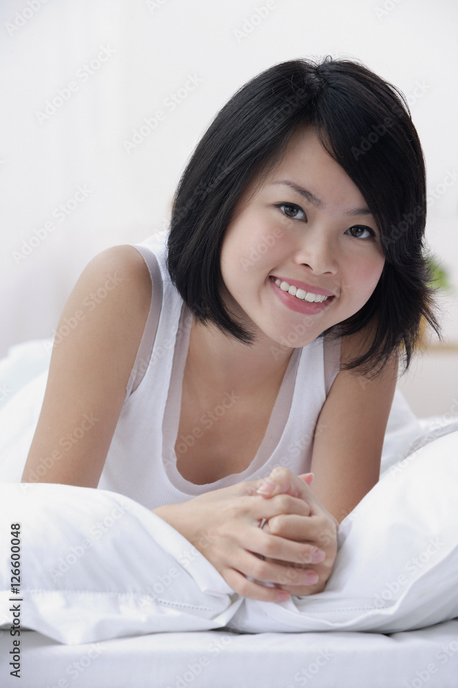 Young woman on bed, smiling at camera Young woman on bed, smiling at camera
