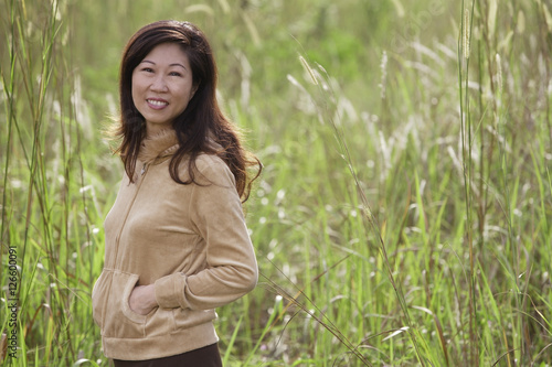 woman standing in tall grass, nature, smiling at camera