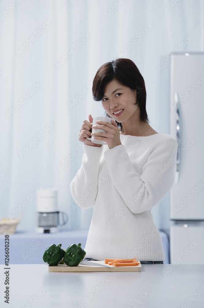 Woman in kitchen, holding a mug, looking at camera Woman in kitchen, holding a mug, looking at camera