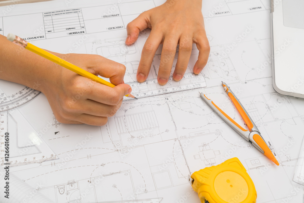 Hand over Construction plans with yellow helmet and drawing tool Hand over Construction plans with yellow helmet and drawing tool